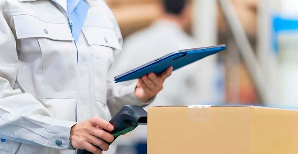 Déménageur professionnel effectuant l'inventaire numérique des biens stockés avec tablette et codes de traçabilité